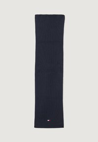 Strikket skjerf i marineblått, rektangulær form, med en liten logo med røde, hvite og blå detaljer nær bunnen. Myk tekstur.