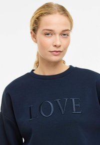 Sweat-shirt bleu marine avec texte "LOVE" embossé, fabriqué en mélange de coton doux, avec un col rond et une coupe décontractée.