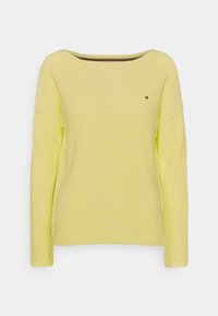 Pull en maille côtelée jaune clair avec manches longues et encolure large et arrondie, doté d'un petit logo sur la poitrine.