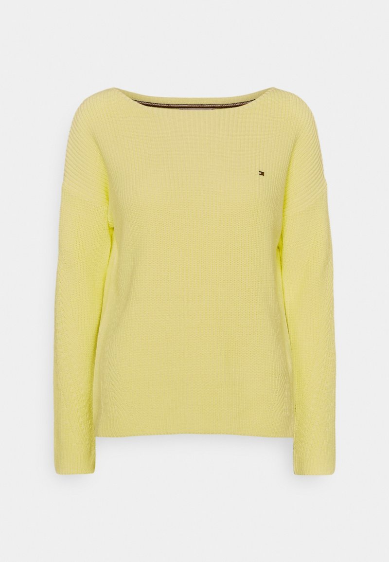 Pull en maille côtelée jaune clair avec manches longues et encolure large et arrondie, doté d'un petit logo sur la poitrine.