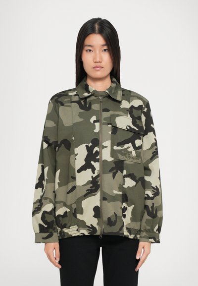 Camo zip-up jack in groene tonen met een borstzak, elastische manchetten en een ontspannen pasvorm. Gemaakt van lichtgewicht stof met een matte afwerking.