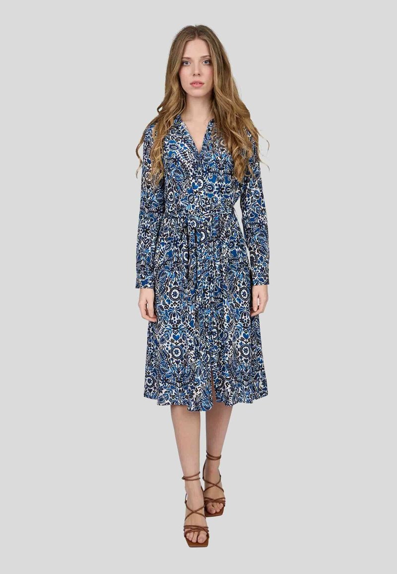 Robe bleu à manches longues avec une taille ceinturée, jupe à longueur genoux, col à boutons et un design évasé pour un mouvement libre.