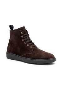 Botines de ante marrón con ojales dorados, cordones negros, suela texturizada negra y una lengüeta trasera para facilitar el calzado.