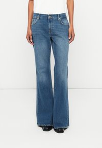 Light blue denim flared jeans with a mid-rise waist, front pockets, and a subtle wash. The fabric has a smooth texture, featuring stitched seams.