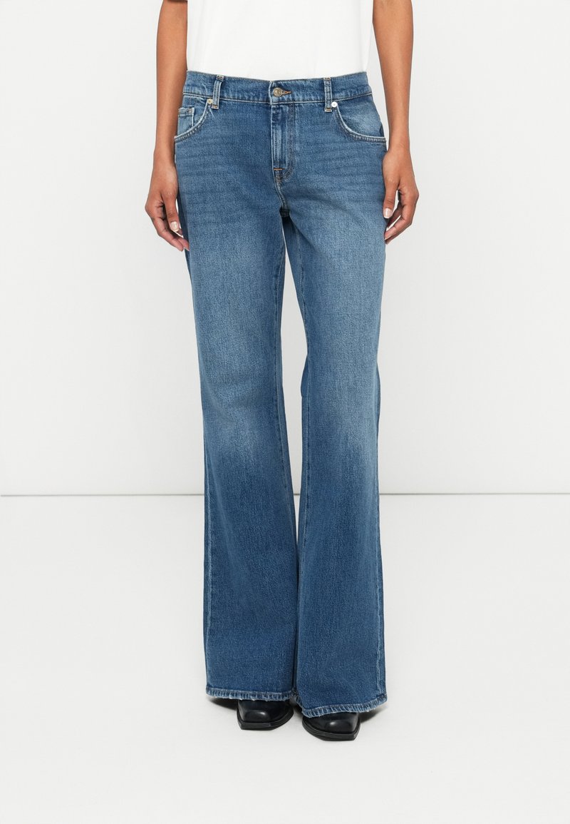 Light blue denim flared jeans with a mid-rise waist, front pockets, and a subtle wash. The fabric has a smooth texture, featuring stitched seams.