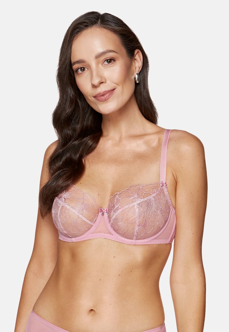 Koronkowy stanik w delikatnym różu z kwiatowym haftem, przejrzystymi miseczkami, wsparciem w postaci fiszbin i regulowanymi ramiączkami; ozdobiony małą kokardką na środku.