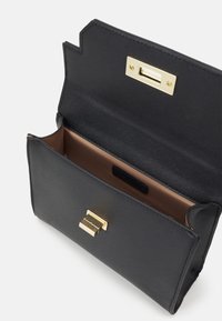 Sac à main synthétique noir avec une finition texturée, quincaillerie dorée et fermeture à rabat. L'intérieur est doublé de marron et comprend un compartiment.