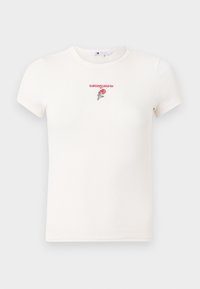 T-shirt blanc à côtes avec des manches courtes, un col rond, et un logo "tommy jeans" brodé rouge avec un détail de rose.
