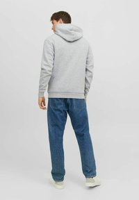 Gray hoodie with a spacious hood, ribbed cuffs, and hem. Paired with blue denim jeans and white sneakers, displaying a casual fit.
