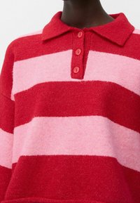 Red and pink striped knitted sweater with a polo collar and four red buttons. Soft texture, boxy fit, and visible seam details.