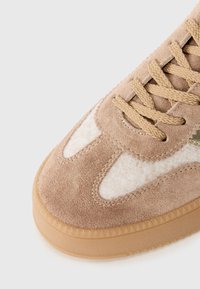 Baskets en daim beige avec accents en feutre blanc, bout rond, semelle plate en caoutchouc beige et lacets texturés. Détail logo doré sur le côté.