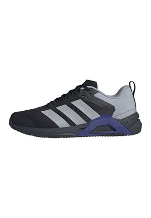 Sort og grå atletiksneaker med tre reflekterende striber, lilla accent nær sålen og grå polstret hælkant.