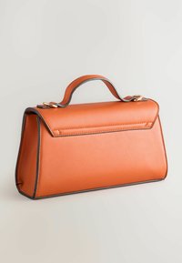 Orange läderhandväska med en strukturerad form, kontrasterande svart kant och ett kort, rundat handtag. Har en lockstängning upptill.