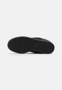 Black sneaker sole with a textured rubber outsole, featuring a geometric pattern and logo imprint, designed for traction and durability.