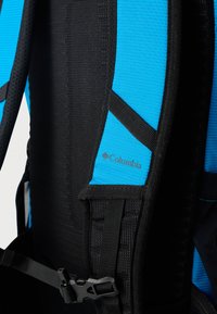 Σακίδιο πλάτης με εξωτερικό περίβλημα από μπλε και μαύρο δίχτυ, διαθέτει ρυθμιζόμενους ιμάντες, μαύρη αγκράφα και λογότυπο Columbia εγχάρακτο στο υλικό.