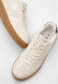 Sneaker beige con tomaia in pelle testurizzata, suola in gomma e lacci abbinati. Caratterizzate da un design minimalista con cuciture laterali sottili.