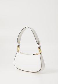 Borsa a mano in pelle bianca con forma curva, rifiniture nere a contrasto e manico corto imbottito. Accenti in hardware dorato visibili.