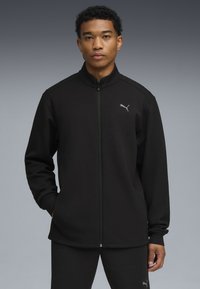 Sorte zip-up jakke lavet af glat stof, med højt krave og PUMA-logo i grå, med lange ærmer og sidelommer.