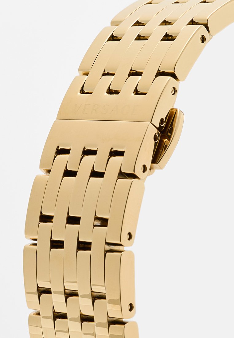 Gouden metalen horlogeband met een ontwerp van in elkaar grijpende schakels. Gladde textuur en gepolijst afwerking. Kenmerkt gegraveerd merk en een sluiting.