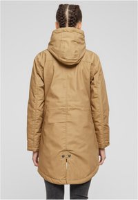 Rjava jopa s kapuco in zadrgo, zoženim pasom ter z zrahljalom na hrbtni strani. Material deluje trpežno s gladko teksturo.