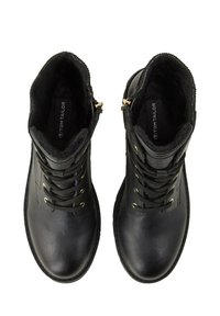 Ein Paar schwarze Leder-Schnürstiefeletten mit goldenen Ösen, seitlichem Reißverschluss und Innenfutter aus Fell, von oben betrachtet.