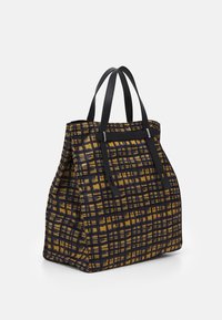 Sac cabas avec un motif à carreaux jaune et marine, doté de poignées en cuir noir et d'une forme structurée. Le tissu texturé ajoute de la dimension.