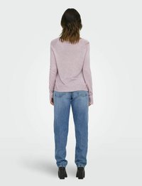 Lichtroze longsleeve top met een losse pasvorm, gecombineerd met blauwe rechte jeans. De outfit bevat effen kleuren en een eenvoudig ontwerp.