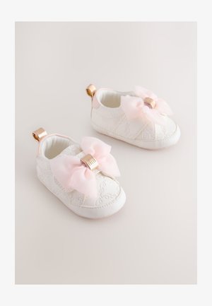 Valged beebijalatsid tekstuurse nahaga, millel on suured roosad paelad ja kuldsed detailid, pehme sisemine vooder ja tagaküljel tõmblukukingad.