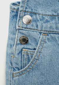 Svetlo modra denim tkanina z vidno teksturo, ki ima sprednji žep, oranžne šive in srebrne gumbe s potiskom "MNG DENIM."