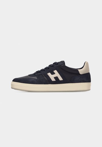Baskets bleu marine avec semelle beige et détail talon, grand logo "H" beige sur le côté, et lacets noirs.