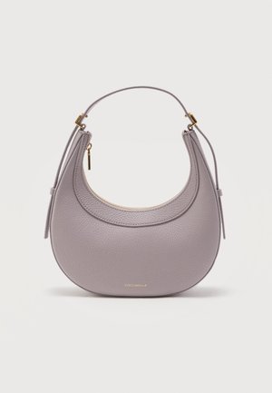 Sac à main en cuir lavande arrondi avec fermeture éclair dorée et anse courte, petit logo de marque doré "Coccinelle" au centre en bas.