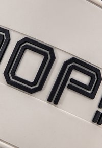 Logo geometrico nero su uno sfondo crema testurizzato, con design esagonali e angolari e elementi sovrapposti.