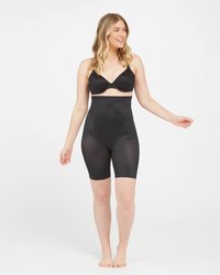 Black shapewear shorts made of smooth, stretchy material with a high waist. Features a seamless design and mid-thigh length.