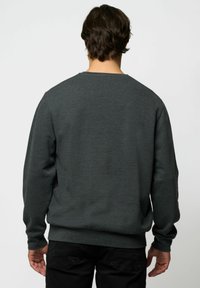 Sötétszürke, laza szabású pulóver, bordázott mandzsettákkal és aljjal. Az anyag texturált hatású, látható logók vagy minták nélkül.