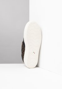 Sneaker nera con un motivo a logo marrone, suola in gomma bianca e fondo testurizzato. Presenta il marchio sul lato e la misura all'interno.