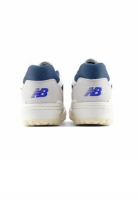 Weiße und marineblaue Sneaker mit einem Obermaterial aus Wildleder und Nylon, gepolstertem Kragen und gummierter Laufsohle mit strukturierten Rillen. Blaues Logo an der Ferse.