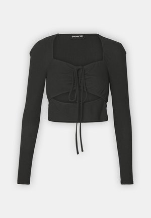Haut noir cropped à manches longues en tissu côtelé, avec un décolleté carré et un détail de lien à l'avant.