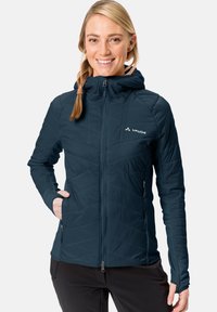 Mornarsko modra insulated jakna s kapuco, z zadrgo spredaj, podolžno prešit vzorec in žepi na straneh z zadrgo. Mehka, lahka tkanina.