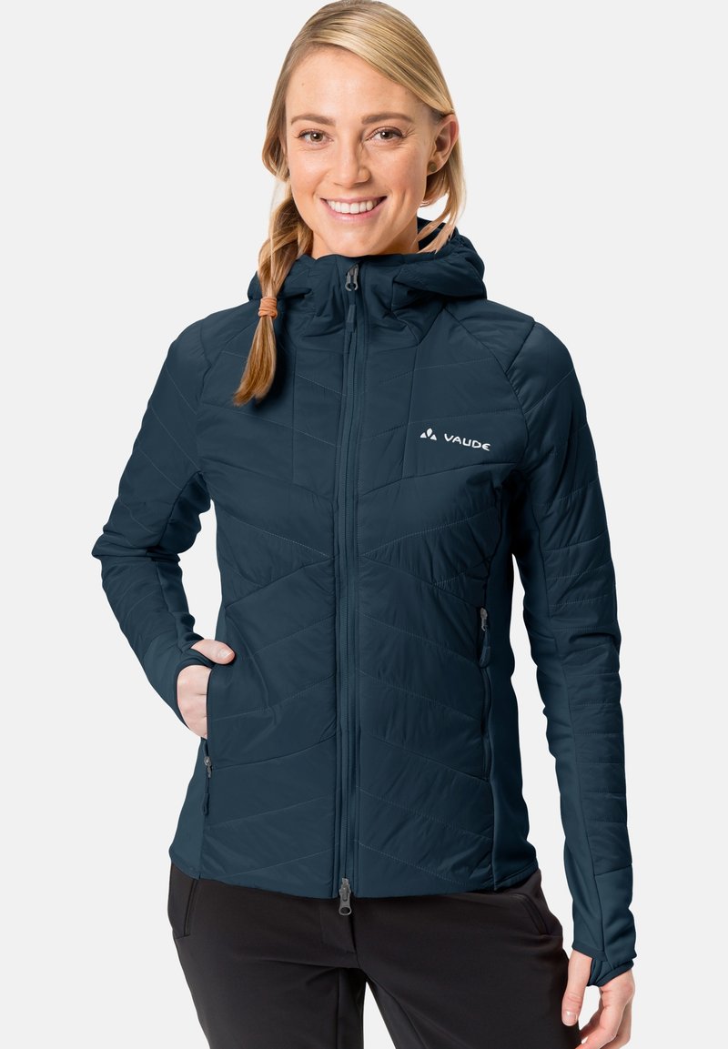 Mornarsko modra insulated jakna s kapuco, z zadrgo spredaj, podolžno prešit vzorec in žepi na straneh z zadrgo. Mehka, lahka tkanina.