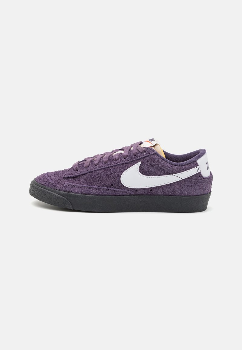 Lila Wildlederschuhe mit einem flachen Design, weißen Nike-Swoosh, schwarzem Gummilaufsohle und kontrastierenden Schnürsenkeln. Keine zusätzlichen Akzente.