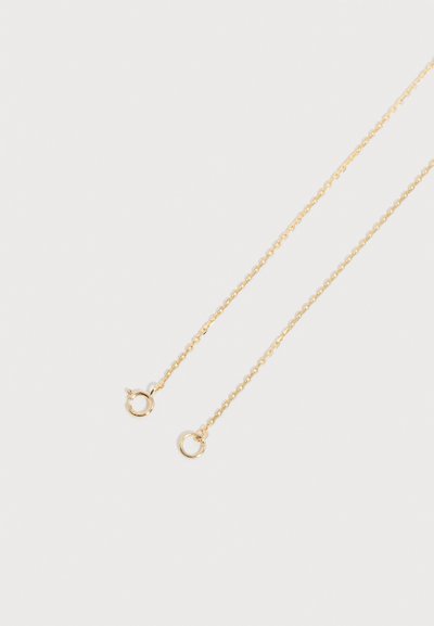 Λεπτή χρυσή αλυσίδα με μικρό στρογγυλό ελατήριο κούμπωμα, τοποθετημένη σε απλό φωτεινό φόντο.