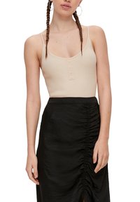 Beige geribbelde tanktop met een ronde hals en knoopdetail, gecombineerd met een zwarte gerimpelde rok met zijwaartse plooien en een split.