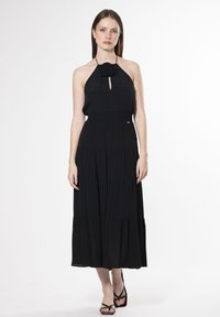 Schwarzes Halterneck-Kleid mit einem Schlüssel-ausschnitt, strukturiertem Stoff und gestuftem Rock. Hat eine florale Akzentuierung am Ausschnitt. Bodentiefe Design.