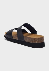 Sandalo nero con suola intermedia in sughero e suola esterna in gomma nera testurizzata. Caratterizzato da ampie cinghie incrociate e una soletta anatomica per il comfort.