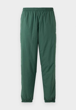 Pantaloni verdi, leggeri, elasticizzati con cintura e polsini arricciati, realizzati in un materiale liscio e resistente all'acqua.