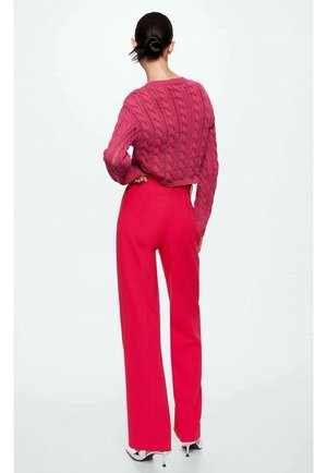 Magenta svetr s pleteným vzorem v kombinaci s jasně růžovými kalhotami s volnými nohavicemi. Tento outfit se vyznačuje texturovaným vzorem a přiléhavým, vysokým pasem.