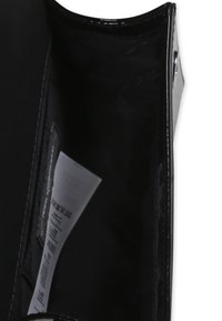 Sac en cuir verni noir avec une finition brillante, doté d'une poche intérieure et d'une doublure en tissu, mettant en valeur un design minimaliste.