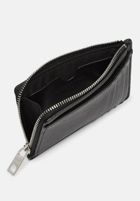 Czarny portfel ze skóry o gładkiej fakturze, z zamkiem na suwak i pionowym żebrowaniem. Wnętrze wyposażone w przegródki na karty i pojemną kieszeń.