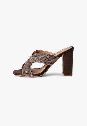 Bruine open-toe mule met hoge blokhak en glinsterende gekruiste bandjes op een witte achtergrond.
