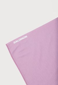 Τμήμα διπλωμένου μοβ υφάσματος με λευκό λογότυπο «Salomon» τυπωμένο στη γωνία, σε λευκό φόντο.